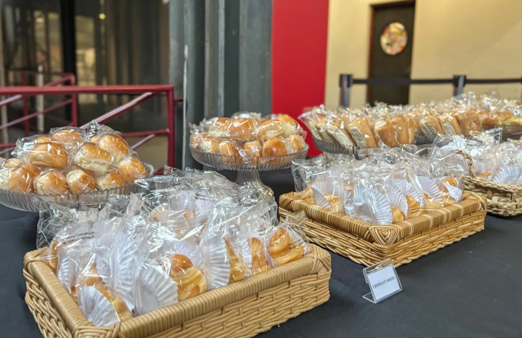 Mesa de coffee break econômico montada com bandejas organizadas de lanches variados para evento corporativo da Bonaliment.